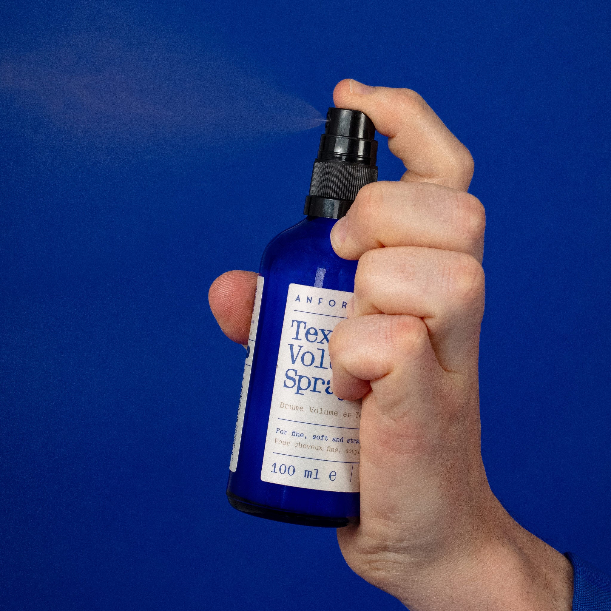 Hand spraying Anforh Texture Volume Spray showing a fine mist coming from the atomiser