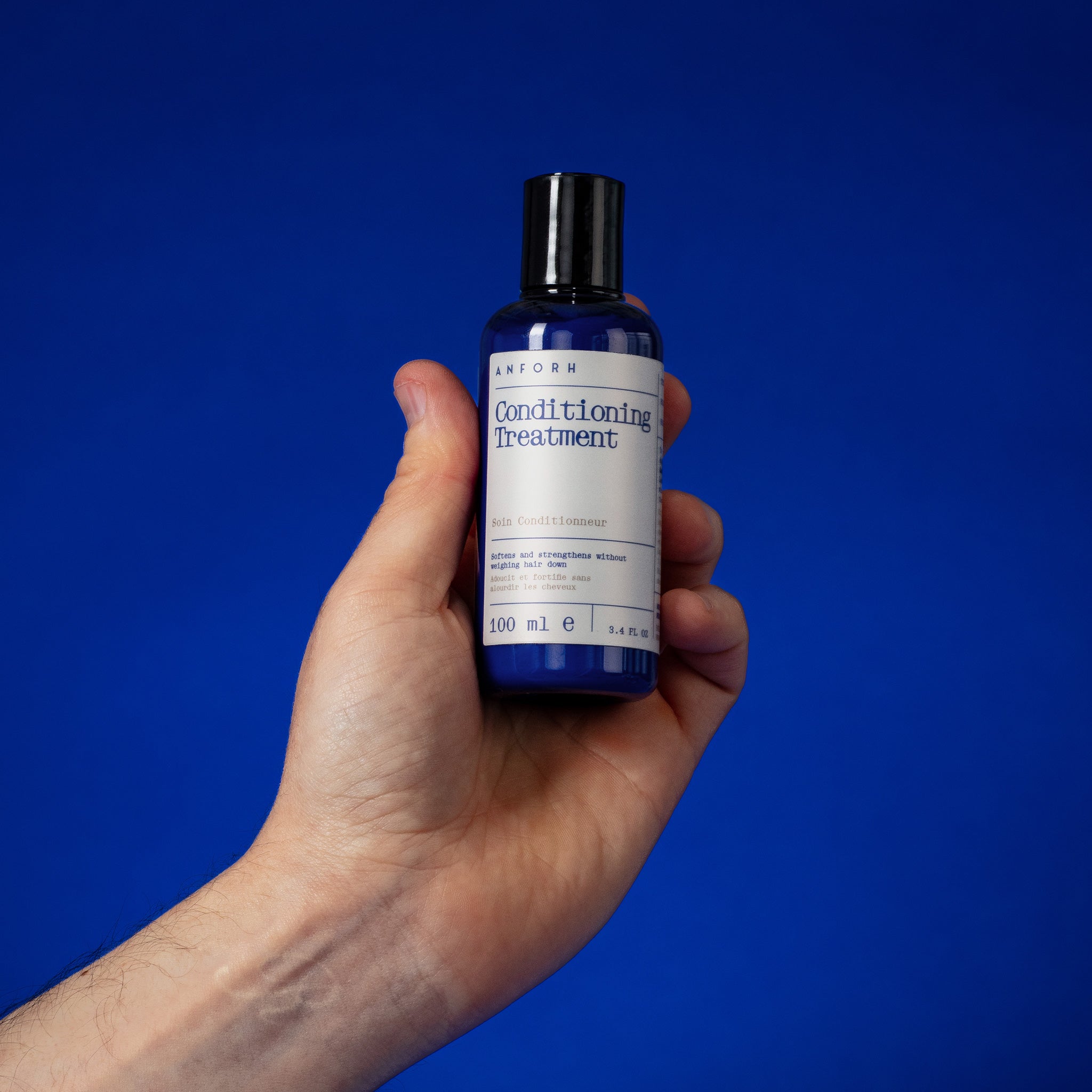 Hand holding the blue plastic bottle of Anforh Conditioning Treatment